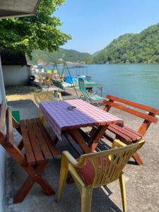 a picnic table and chairs next to a body of water at Drinska oaza in Zvornik