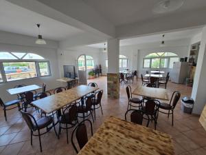 a dining room with tables and chairs and windows at Vila Sokrati in Mursi