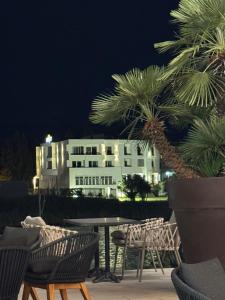 a building at night with chairs and a table and palm trees at Hotel Porto A in Ulcinj