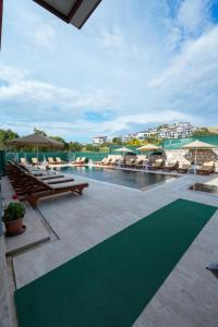 a swimming pool with tables and umbrellas at a resort at İNDAĞ APART AİLE Oteli in Seferihisar