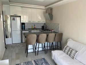 a kitchen with a bar with stools and a couch at İNDAĞ APART AİLE Oteli in Seferihisar