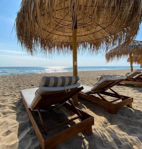 two lounge chairs and an umbrella on a beach at Apartment Villa al Mare 1 in Shkorpilovtsi