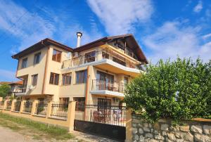 a large yellow building with a fence in front of it at Apartment Villa al Mare 1 in Shkorpilovtsi