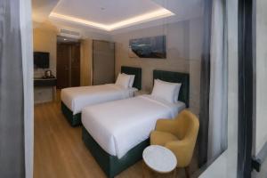 a hotel room with two beds and a chair at T h e V o i d Hotel - Just Steps From Osmanbey Metro Station in Esenyurt