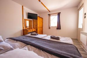 a bedroom with two beds and a television and a window at Gyarmati Vendégház Sirok in Sirok