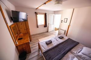 a bedroom with a bed and a flat screen tv at Gyarmati Vendégház Sirok in Sirok