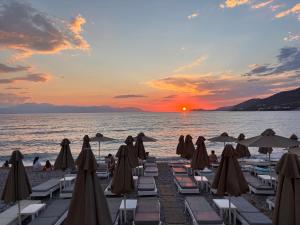 a beach with chairs and umbrellas at sunset at The Onyx Residence in Loutraki
