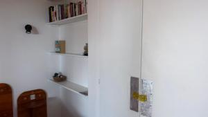 a room with white walls and shelves with books at auxcheneslieges in Lecci