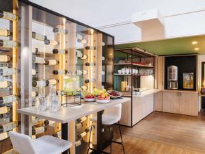 a kitchen with a table and chairs and wine racks at ibis La Roche Sur Yon Vendespace in Mouilleron-le-Captif