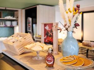 a table with a blue vase and a plate of food at ibis La Roche Sur Yon Vendespace in Mouilleron-le-Captif