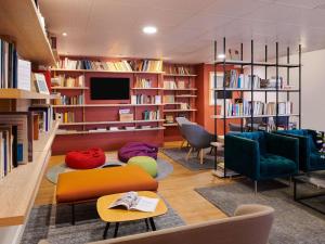 a library with chairs and a tv and books at ibis La Roche Sur Yon Vendespace in Mouilleron-le-Captif