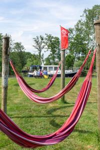 a couple of red hammocks in a park at Woonboot de Waterwoning in Irnsum