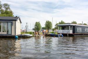 a group of people standing in the water next to a house at Woonboot de Waterwoning in Irnsum