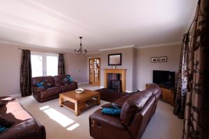 un soggiorno con divani in pelle e TV di Brae Cottage a Dunvegan