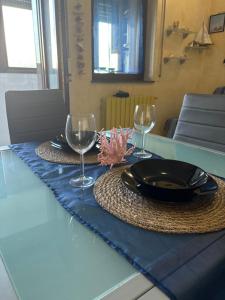 a table with a plate and two wine glasses on it at Sea & spiagge a 200m Stella del Salento in Brindisi
