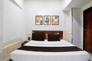 a bedroom with a large white bed with black pillows at Hotel O Grand Villa in Mumbai