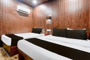 two beds in a room with wood paneled walls at Hotel O Grand Villa in Mumbai