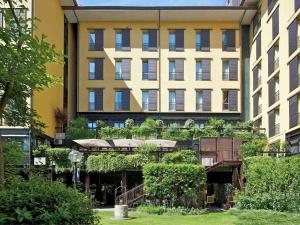 a large building with a lot of plants in front of it at Mercure Bologna Centro in Bologna