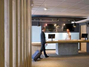 a man with a suitcase walking past a counter at ibis Bordeaux Centre - Gare Saint-Jean in Bordeaux