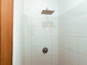 a white tiled shower with a black knob at Sunset Surfhouse Morocco in Tamraght Ouzdar +21 photos