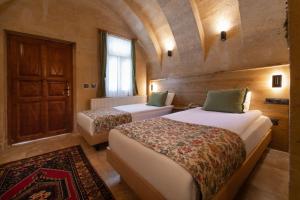 a bedroom with two beds and a door and a rug at Melis Cave Hotel in Ürgüp +113 photos
