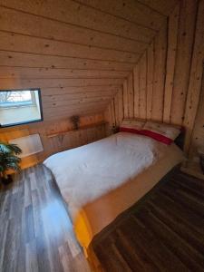 a bed in a wooden cabin with a window at Le chalet chartreux in Sarcenas