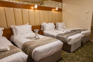 a hotel room with three beds in a room at Grand Zowar Hotel - فندق جراند زوار للضيافة السياحي in Medina