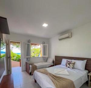 a bedroom with a bed and a couch and a window at Pousada Do Joe in Morro de São Paulo