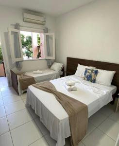 a bedroom with two beds and a window at Pousada Do Joe in Morro de São Paulo