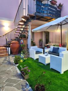 a patio with white chairs and an umbrella at B&B Casa Lina in Sarroch