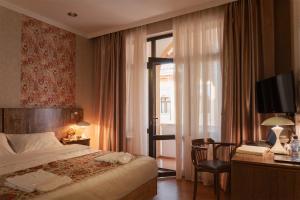a hotel room with a bed and a desk with a television at Omar Khayyam Hotel in Bukhara