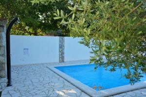 a swimming pool in front of a white wall at Apartments & Villa Tisno in Obrovac
