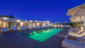 a pool with lounge chairs and a resort at night at Zefyria Luxury Suites in Zefiría