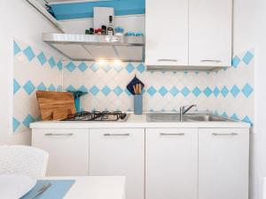 a kitchen with white cabinets and blue and white tiles at Sweet home Santa Lucia in Santa Lucia