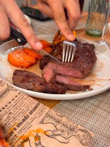 a plate of food with a fork and steak at The Pines Hotel in Culla