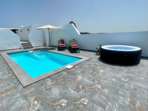 a pool with two chairs and an umbrella on a patio at Apartment Orquidia - Rural Guest Apartment in Tías