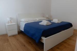 a white bedroom with a blue bed with towels on it at Mara's home in San Salvo
