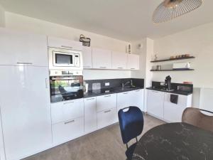 a kitchen with white cabinets and a microwave at La Perle bleue in Berck-sur-Mer +4 photos