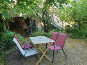 three chairs and a wooden table with a table at Unser Obervolkacher Ferienhaus - Hideaway & Gartenoase mit Wohlfühlflair und Herz für Hunde in Volkach
