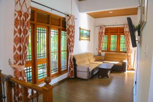 a living room with a couch and a tv at Canal Side Guest House Polonnaruwa in Polonnaruwa