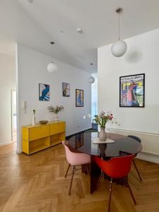 a dining room with a glass table and red chairs at Bauhaus Suite Dessau in Dessau