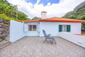 a chair sits on the patio of a white house at Casa da Floresta in Machico