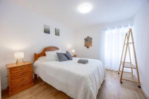 a white bedroom with a bed and a ladder at Casa da Floresta in Machico