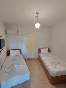 a room with two beds and a tv and a door at Begonvil Otel in Emin Sitesi