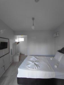 a white bedroom with a large bed with white sheets at Begonvil Otel in Emin Sitesi
