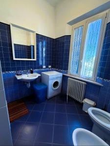 a blue tiled bathroom with a toilet and a sink at Domus Dafne Apartment in Senigallia +37 photos