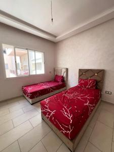 two beds in a bedroom with red sheets at Mohammedia Luxury Suite in Mohammedia