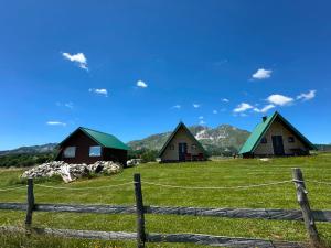 a group of cottages in a field with a fence at Mountain peaceful cottages in Žabljak