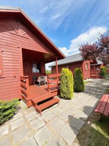 a red building with a bench and a patio at Mandarynka OW in Jarosławiec