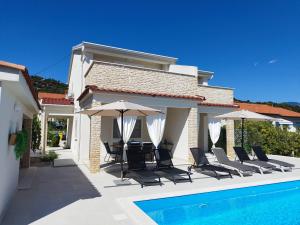 a villa with a swimming pool with chairs and umbrellas at Holiday house Altea , Barbat on the Island Rab in Rab